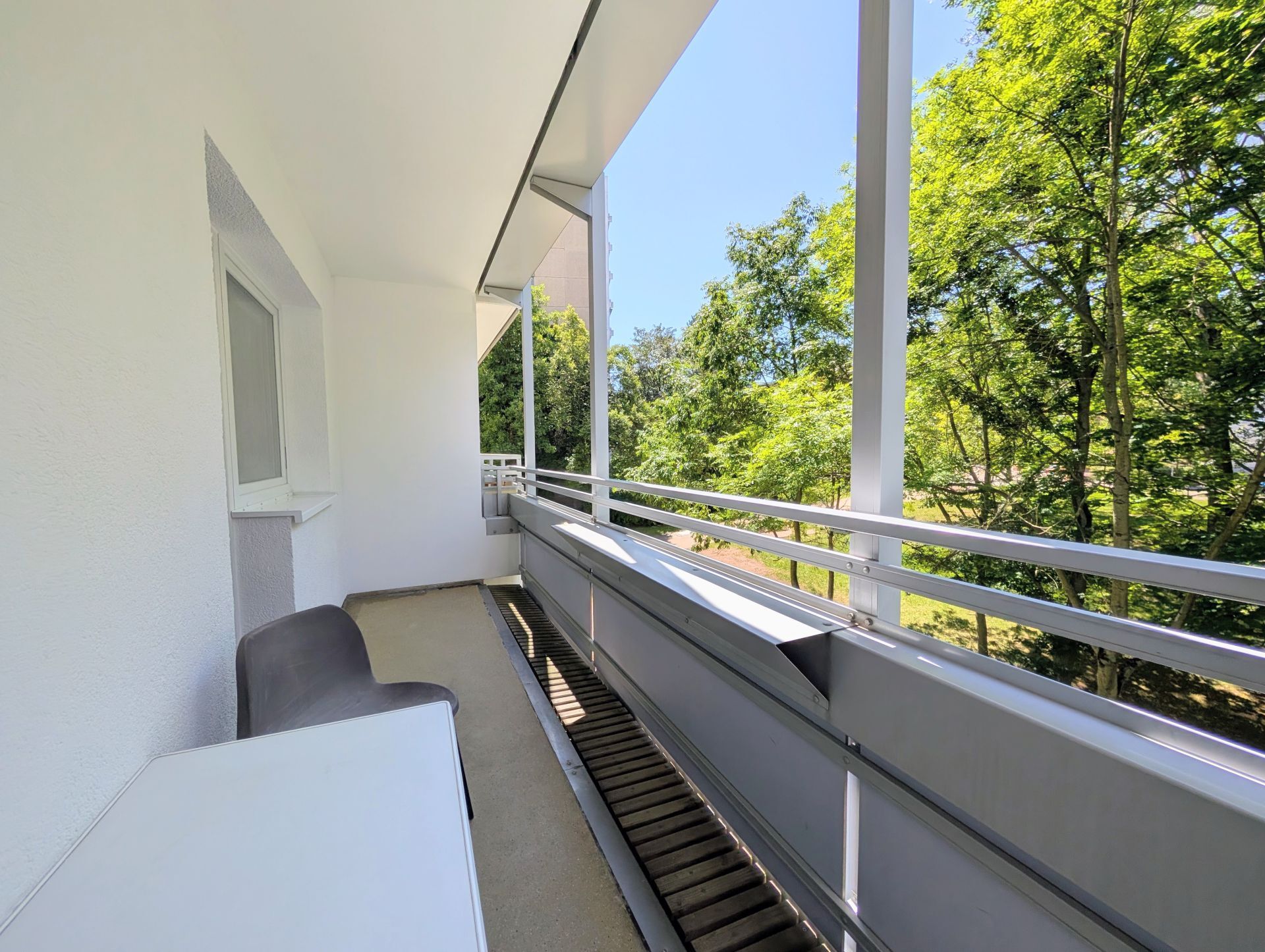 Loggia mit Blick ins Grüne sowie einem Tisch mit Stuhl