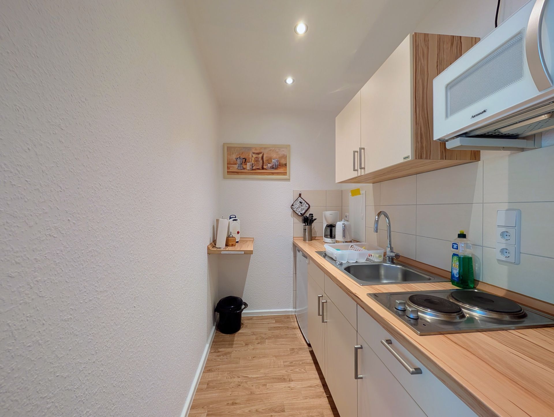 Küchenbereich mit Einbauküche, LED-Deckenspots und Bild an hinterer Wand