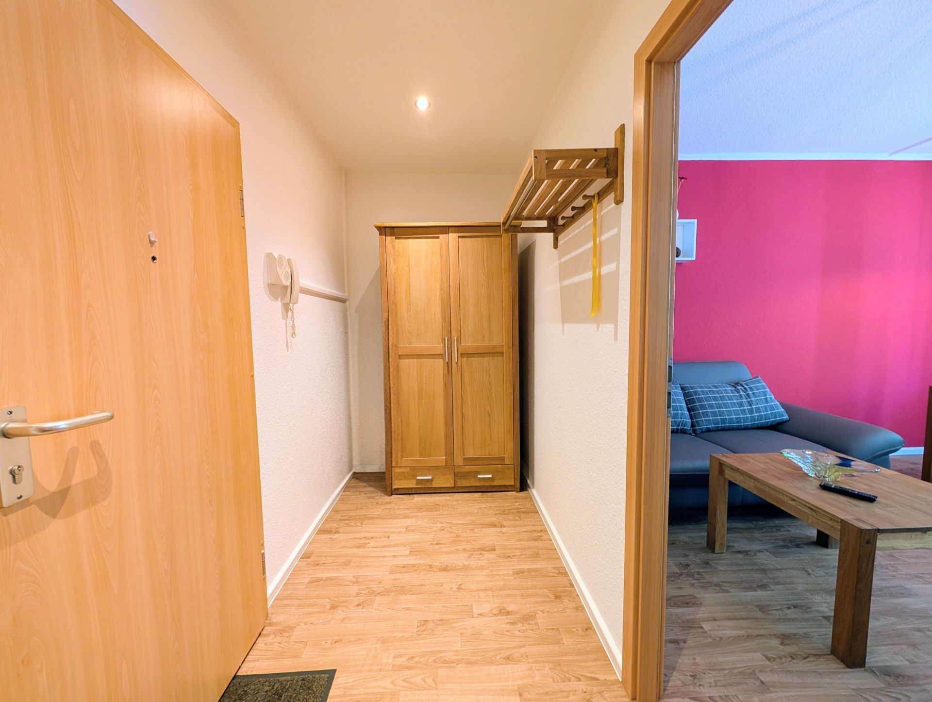 hinterer Teil des Flurs mit Blick auf Flurgarderobenschrank sowie rechts seitlichem Blick ins Wohnzimmer